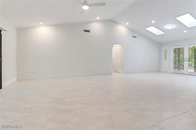 spare room featuring french doors, ceiling fan, brick wall, and vaulted ceiling