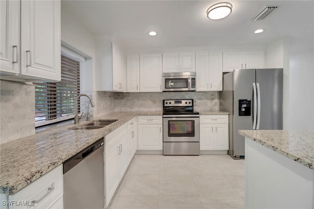 kitchen with appliances with stainless steel finishes, light stone countertops, sink, and white cabinets