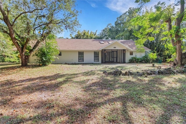 rear view of property featuring a lawn and a sunroom