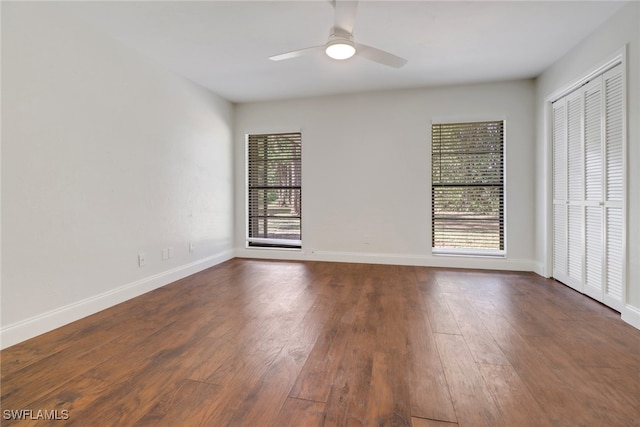 empty room with dark wood-type flooring, a wealth of natural light, and ceiling fan