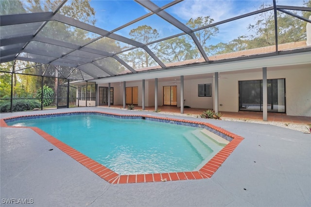 view of swimming pool with ceiling fan, glass enclosure, and a patio area