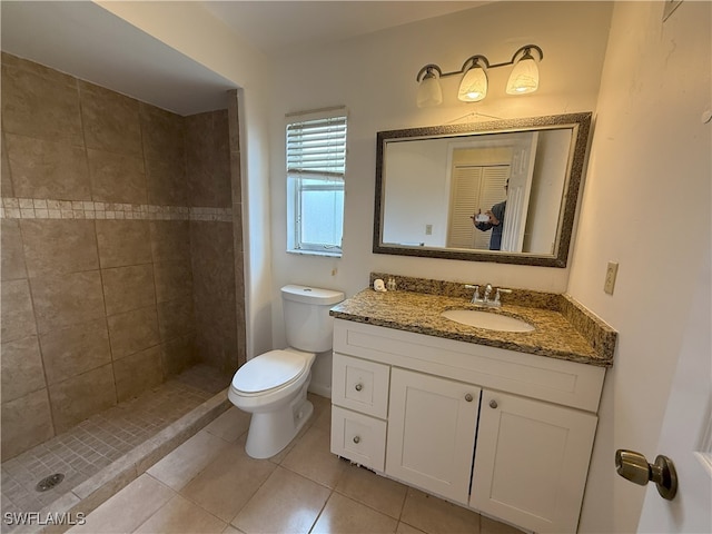 bathroom featuring vanity, toilet, tile patterned flooring, and a tile shower