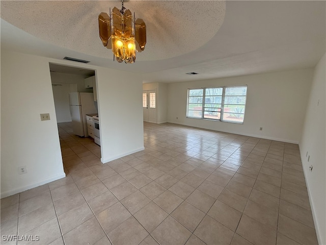 empty room with light tile patterned floors, a notable chandelier, and a textured ceiling