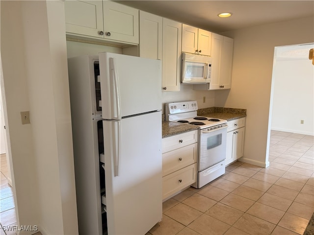 kitchen with white cabinetry, dark stone countertops, light tile patterned floors, and white appliances