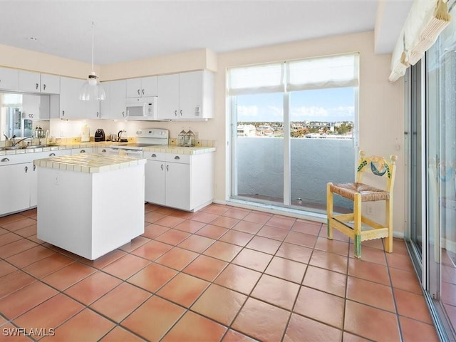 kitchen with white cabinetry, white appliances, tile countertops, and a center island