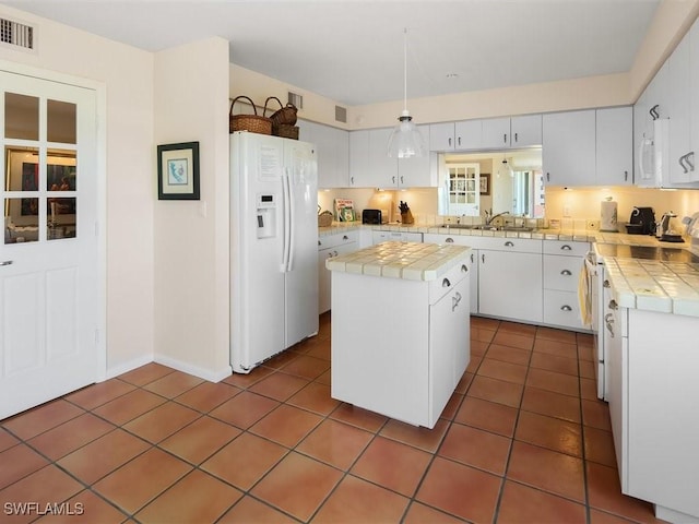 kitchen with white cabinetry, white refrigerator with ice dispenser, a center island, and tile patterned flooring