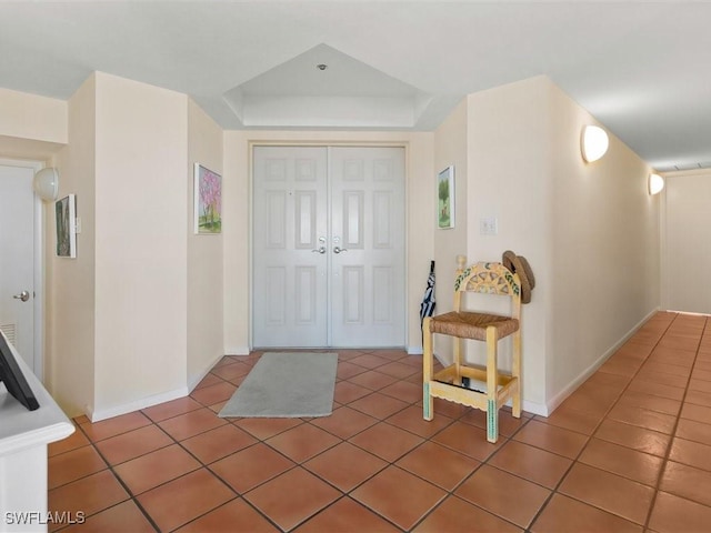 foyer featuring a tray ceiling and dark tile patterned floors