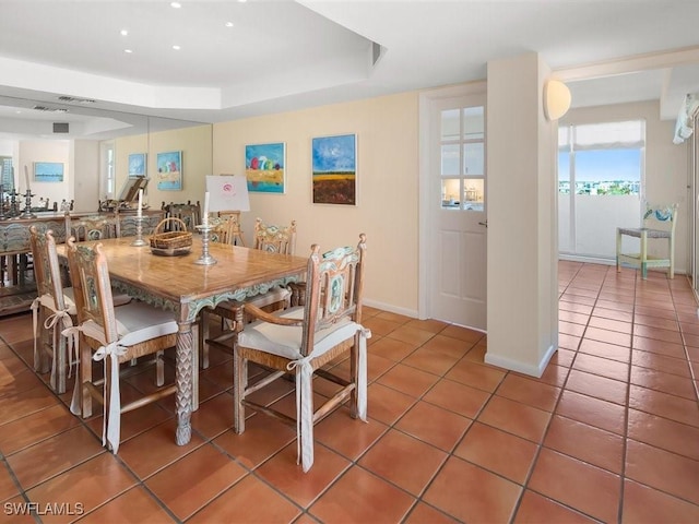 dining space featuring tile patterned floors and a raised ceiling