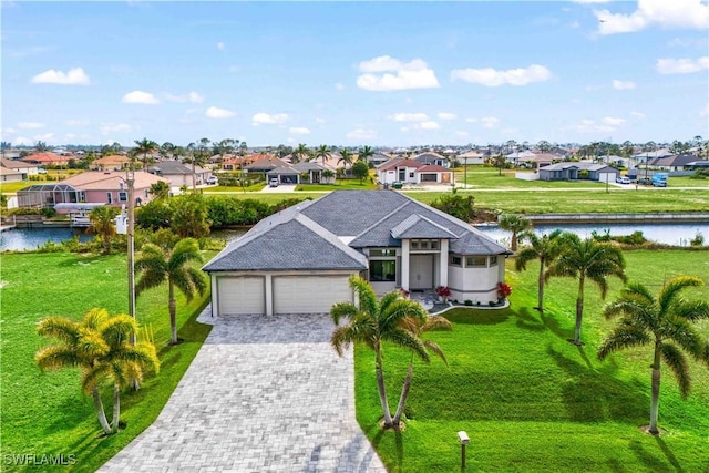 view of front facade with a garage, a front yard, and a water view