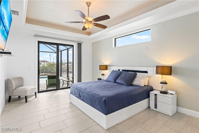 bedroom featuring multiple windows, a raised ceiling, and ceiling fan