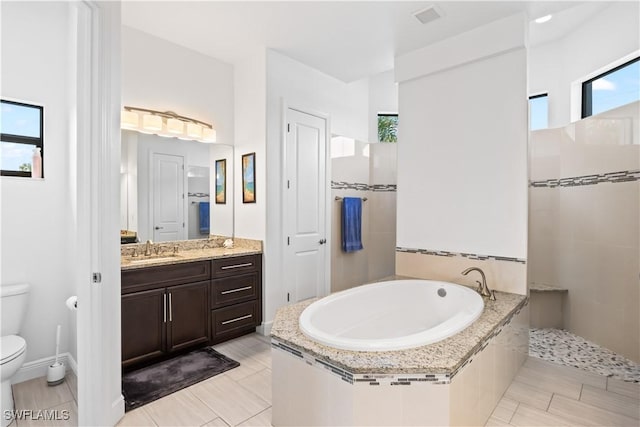 bathroom featuring a relaxing tiled tub, vanity, and toilet