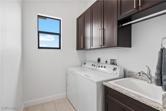 laundry area with cabinets, washing machine and dryer, and sink