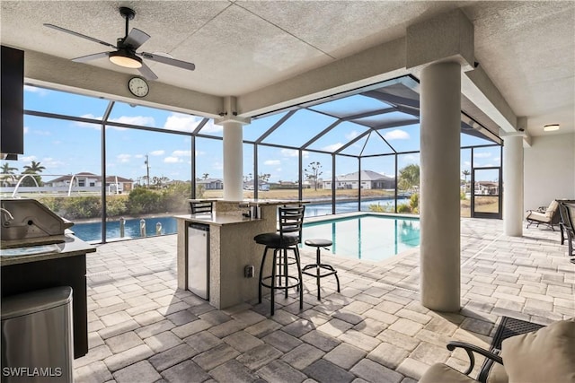 view of pool with a bar, a lanai, a patio area, and ceiling fan