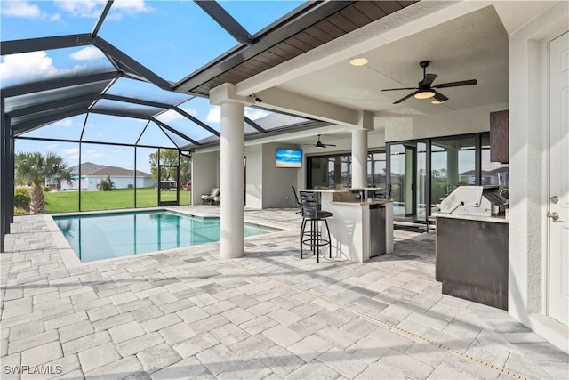 view of swimming pool with a patio area, exterior kitchen, glass enclosure, and exterior bar