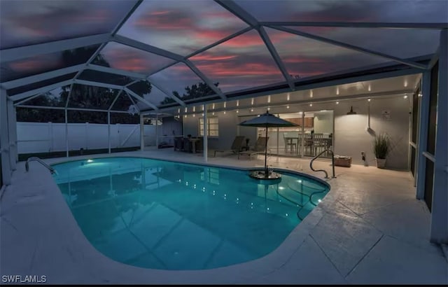 pool at dusk featuring a patio and a lanai