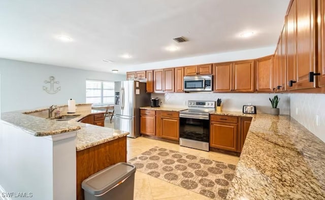 kitchen with kitchen peninsula, appliances with stainless steel finishes, sink, light tile patterned floors, and light stone counters