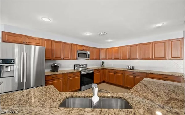 kitchen with light stone countertops, sink, and stainless steel appliances