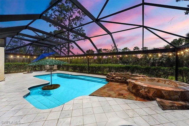 pool at dusk featuring a patio, an in ground hot tub, and glass enclosure