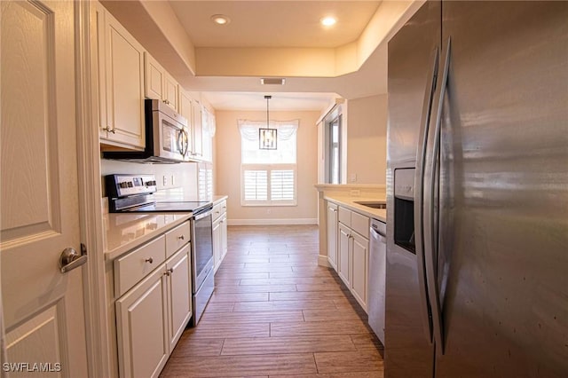 kitchen featuring white cabinetry, stainless steel appliances, decorative light fixtures, and dark wood-type flooring