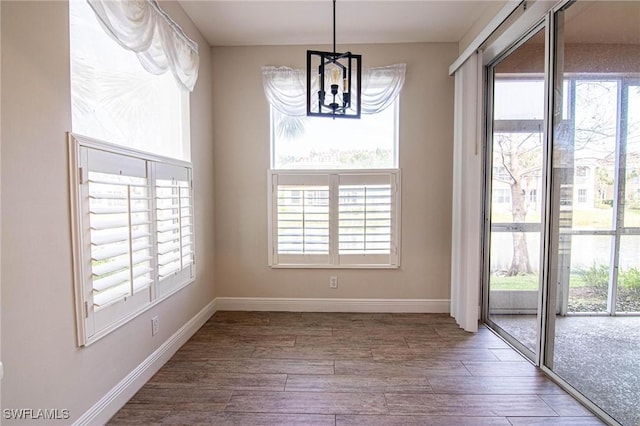 unfurnished dining area with hardwood / wood-style floors and a notable chandelier