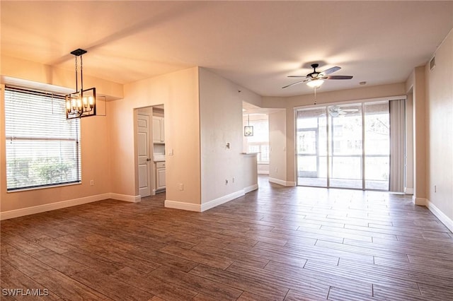 unfurnished living room featuring ceiling fan with notable chandelier and dark hardwood / wood-style floors