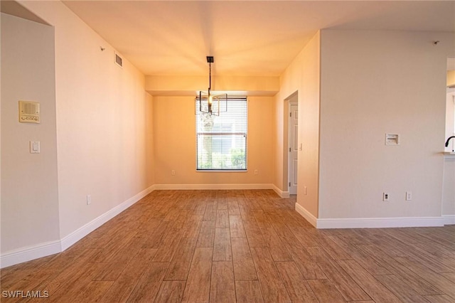 unfurnished dining area with a notable chandelier and wood-type flooring