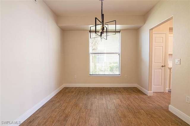 unfurnished dining area with a notable chandelier and wood-type flooring