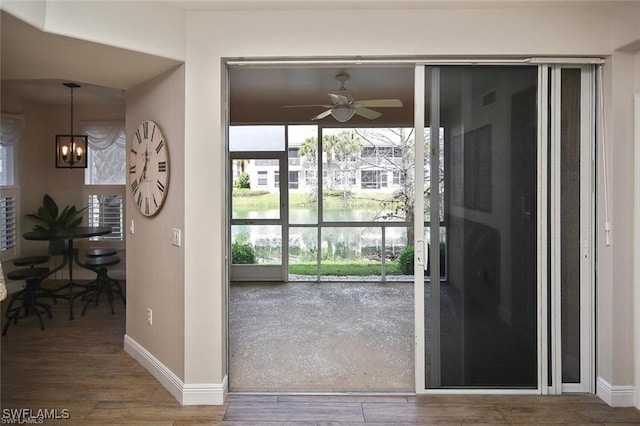 doorway to outside featuring wood-type flooring and ceiling fan with notable chandelier