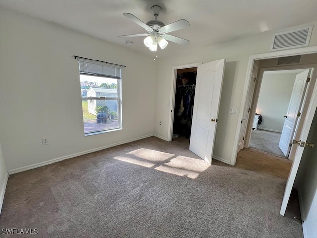 unfurnished bedroom featuring a walk in closet, ceiling fan, light colored carpet, and a closet