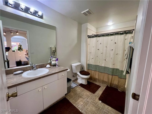 bathroom featuring toilet, a shower with shower curtain, and vanity