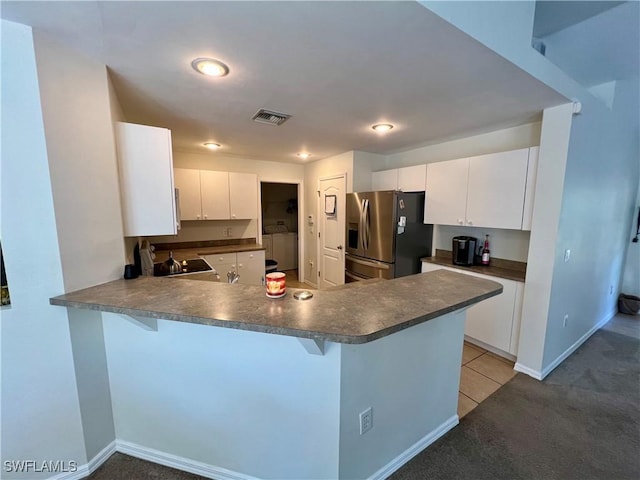 kitchen with stainless steel fridge with ice dispenser, white cabinetry, washer / dryer, and kitchen peninsula