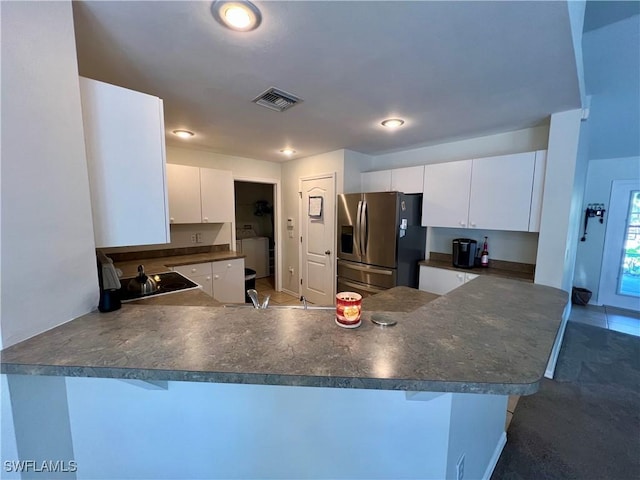 kitchen featuring a kitchen bar, white cabinetry, sink, kitchen peninsula, and stainless steel fridge