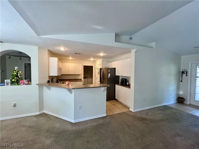 kitchen with white cabinetry, light carpet, a kitchen breakfast bar, kitchen peninsula, and stainless steel refrigerator