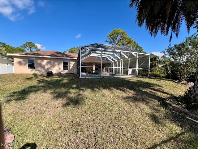 back of property with glass enclosure, a lawn, and a patio area