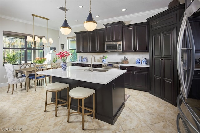 kitchen with sink, tasteful backsplash, appliances with stainless steel finishes, an island with sink, and pendant lighting