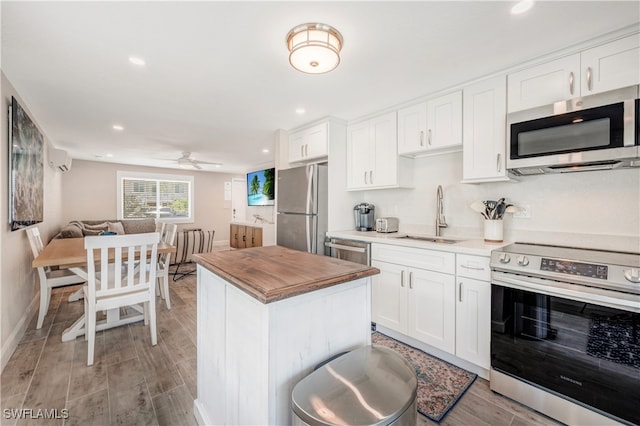 kitchen with butcher block countertops, sink, ceiling fan, appliances with stainless steel finishes, and white cabinets