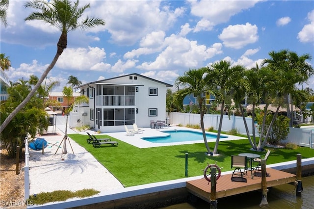 back of house featuring a balcony, a yard, a fenced in pool, a sunroom, and a patio area