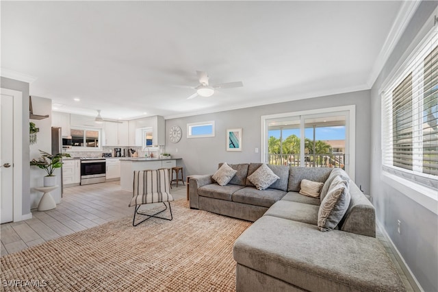 living room featuring sink, crown molding, and ceiling fan