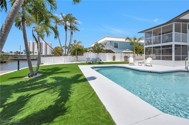 view of pool featuring a water view, a sunroom, a yard, and a patio area