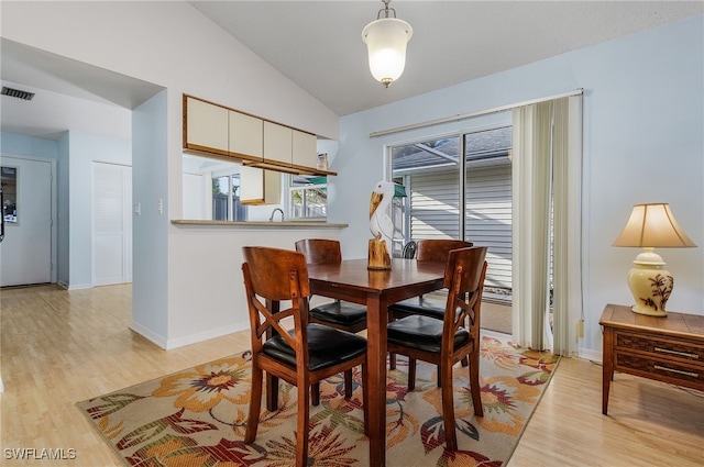 dining space featuring lofted ceiling and light hardwood / wood-style flooring