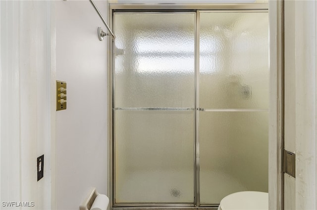 bathroom featuring toilet and an enclosed shower