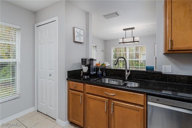 kitchen featuring decorative light fixtures, sink, dark stone counters, stainless steel dishwasher, and light tile patterned floors