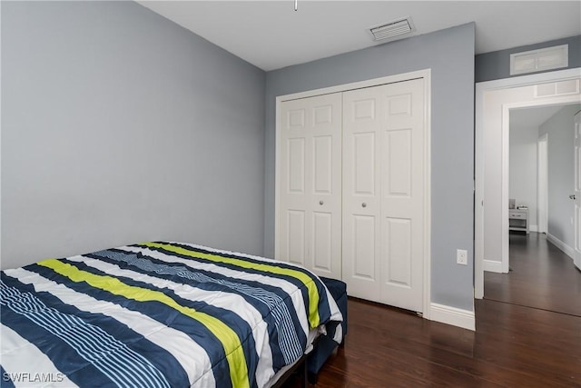 bedroom with dark hardwood / wood-style floors and a closet