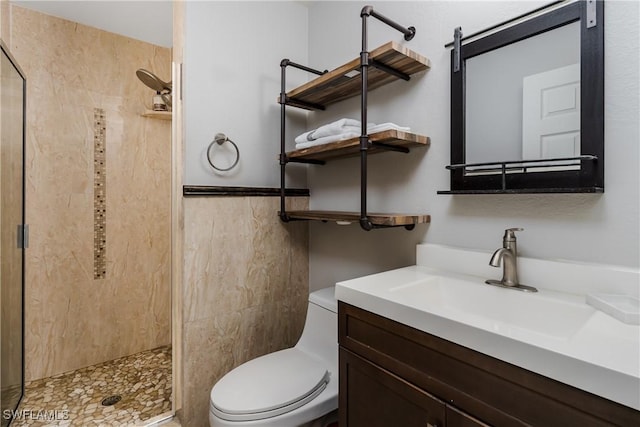 bathroom with vanity, toilet, and tiled shower