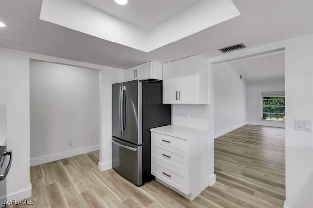 kitchen with white cabinetry, stainless steel refrigerator, and light hardwood / wood-style flooring