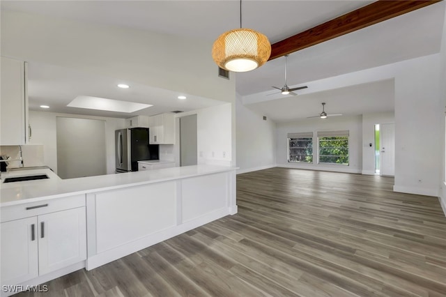 kitchen with sink, white cabinets, beamed ceiling, and stainless steel refrigerator