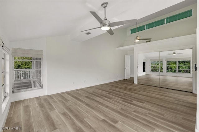 unfurnished living room with ceiling fan, high vaulted ceiling, and light hardwood / wood-style flooring