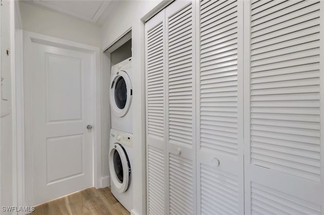 clothes washing area with light hardwood / wood-style flooring and stacked washer and clothes dryer