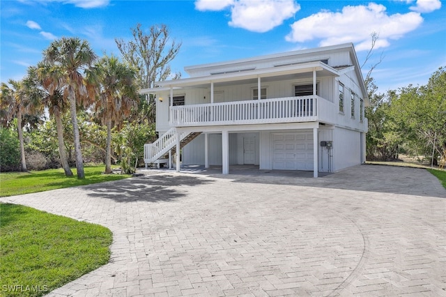 raised beach house featuring covered porch and a garage