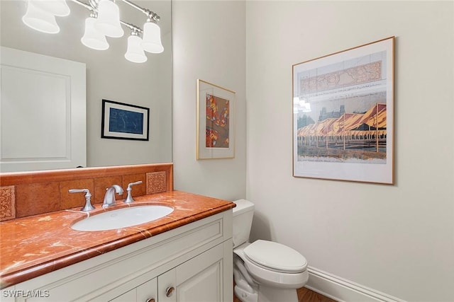 bathroom featuring baseboards, vanity, and toilet